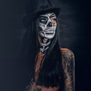 Portrait of female with skull make up in top hat on Halloween.