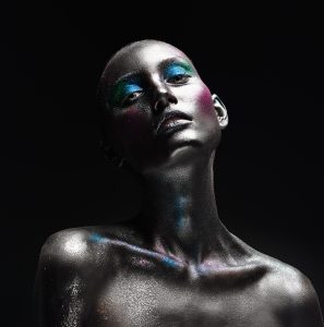 Beautiful fashion woman model with sparkling glitter makeup on black background. Makeup and cosmetics. Body art project.